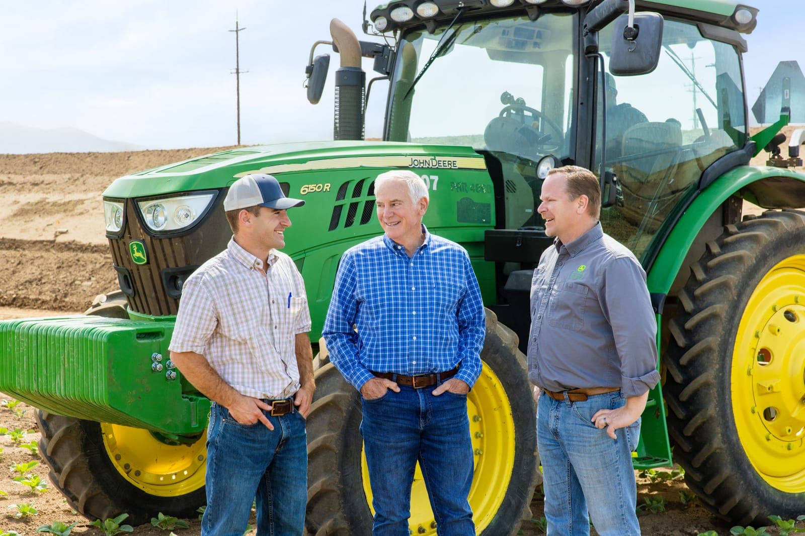 Agricultural team beside a John Deere tractor